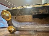 a black marble bench with gold wheels on a wooden floor