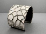 bracelet manchette en argent orné d'un motif géométrique sur un fond gris
