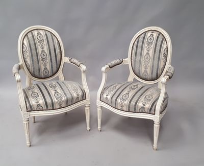 une paire de chaises peintes en blanc, avec des coussins rembourrés à rayures
