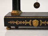 a black and gold clock with a pendulum hanging from it ' s side