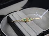 une broche dorée et verte dans un écrin noir