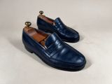a pair of blue loafers with a gold ball on the sole