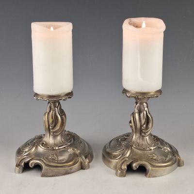 pair of silver candles with candlesticks on stands on a table