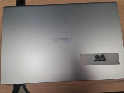 un ordinateur portable argenté posé sur un bureau en bois, à côté d'un clavier