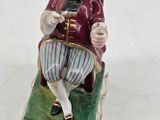 a figurine of a man sitting on a chair with a pipe in his hand