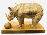 une statue représentant un rhinocéros avec une balle posée sur une table