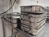 several pots and pans are stacked on a metal shelf in a kitchen