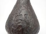 un vase brun posé sur une surface blanche
