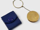 gold plated coin and blue leather case on a white surface