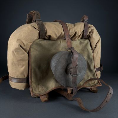 an old backpack with a hat on top of it sitting on a table
