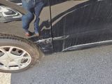 a man standing next to a black car with a broken door