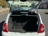 une voiture blanche dont le coffre est ouvert, garée sur un parking