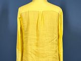 a yellow shirt on a mannequin stand against a blue wall