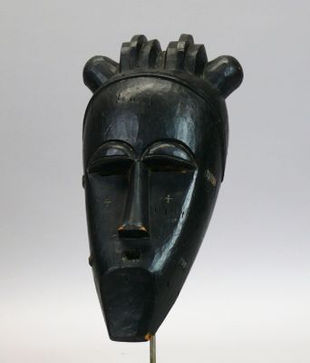 Masque en bois dur à patine noire figurant un visage allongé…