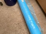un rouleau de plastique bleu posé par terre à côté d'une boîte