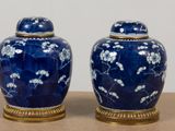 two blue vases with white flowers on them sitting on a table