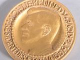 médaille d'or représentant le profil d'un homme sur fond blanc