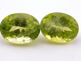 a pair of two green gems sitting on top of a white surface
