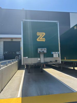 a green semi truck that is parked in front of a building