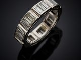 a white gold ring with baguets of diamonds on a black surface