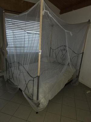 un lit muni d'une moustiquaire, dans une chambre