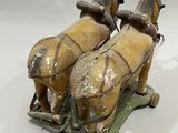 two figurines of horses pulling a sleigh on a white surface