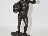 statue en bronze représentant un garçon tenant un ballon de football sur un rocher