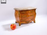 une petite commode avec un plateau en marbre, à côté d'une pomme