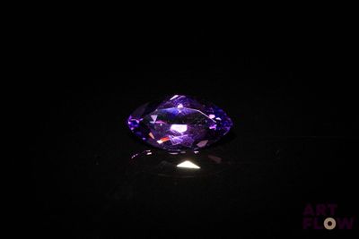 un diamant violet sur une surface noire, dans l'obscurité