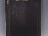 an old black book with writing on it sitting on top of a table