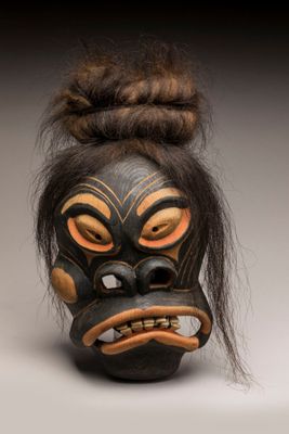 un gros plan d'un masque aux cheveux longs posé sur une surface blanche