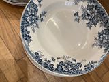 four blue and white plates are stacked on a wooden table