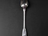 a silver spoon with a spoon handle on a black surface