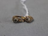 un gros plan sur une paire de boucles d'oreilles en or posées sur une surface grise
