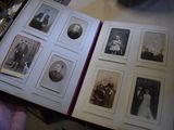 someone is holding a book with a bunch of old photos inside of it