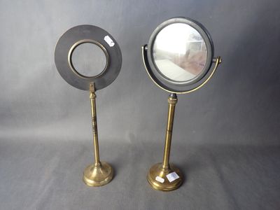 une paire de miroirs grossissants en laiton sur pied, sur fond gris