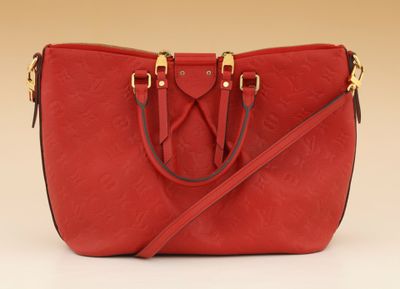 a red purse with gold handles and a strap