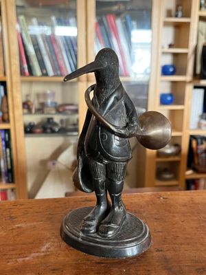 statue d'un homme avec un oiseau sur la tête, tenant un bol