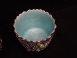 a blue bowl sitting on a black table next to a pine cone