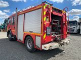 a red fire truck parked in a lot with other trucks in the background