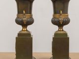 pair of antique bronze vases on pedestals on wooden table