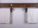 two white towels hanging on a wooden shelf above a toilet paper holder