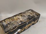 an old black and gold box sitting on top of a white table