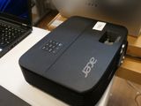 un petit projecteur posé sur un bureau, à côté d'un ordinateur portable