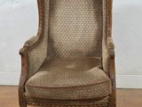an old fashioned chair with a brown upholstered seat and a beige upholstered back