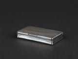 an image of a silver cigarette case sitting on top of a black table