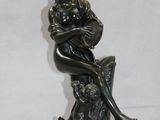 statue en bronze représentant une femme assise sur un rocher avec un chien