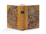 un vieux livre ouvert, dont la couverture laisse apparaître un motif décoratif