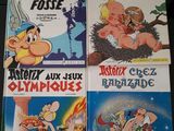 Quatre albums de bandes dessinées sont empilés les uns sur les autres sur une table