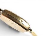 a close up of a gold watch on a white surface